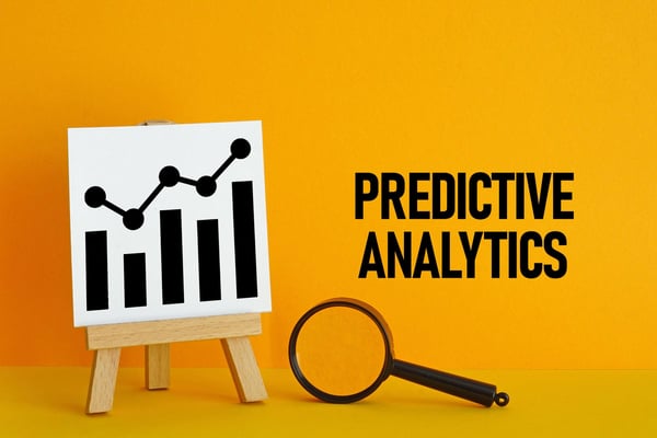 Bar chart on an easel and the words Predictive Analysis on an orange background