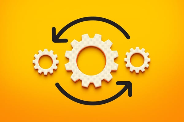 Three light tan gears on an orange background with a black arrow underneath them