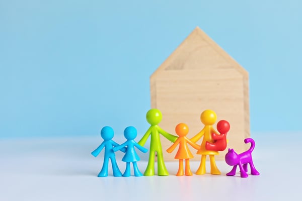 Colorful doll figurines in front of a wooden house,