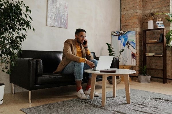 Businessman working from home sitting in front of a laptop while talking on the phone