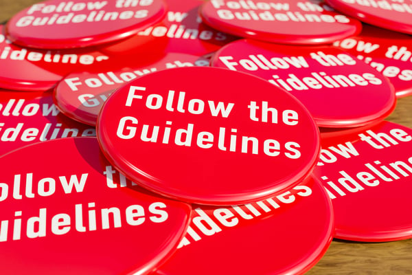 Red badges laying on the table with the message follow the guidelines