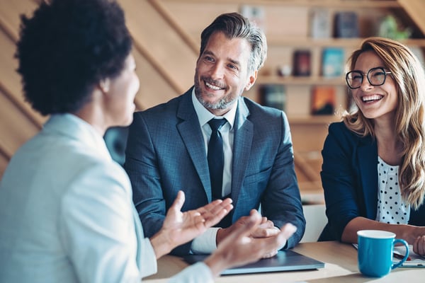 Dos empleadas y un empleado de empresa hablando del éxito de la empresa