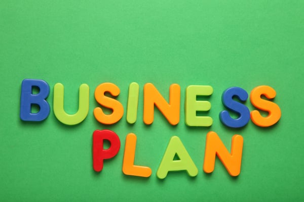 Multi-colored letters on a green background spell out business plan 1