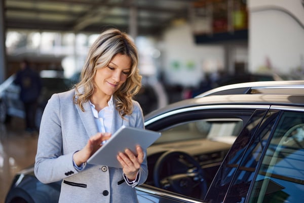 Car saleswoman using a tablet to record information about a car