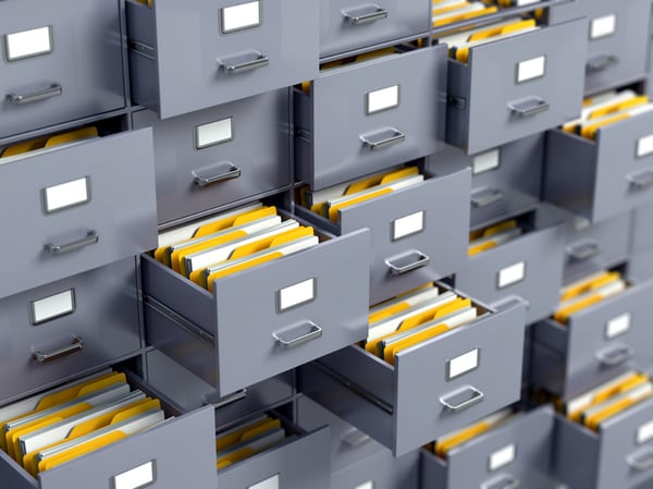Gray file cabinets that contain yellow folders that hold paper