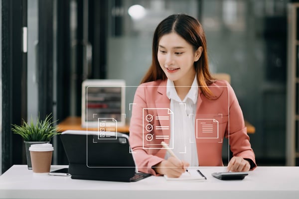 1 Young businesswoman at a desk viewing a laptop with transparent drawing showing electronic signature icons