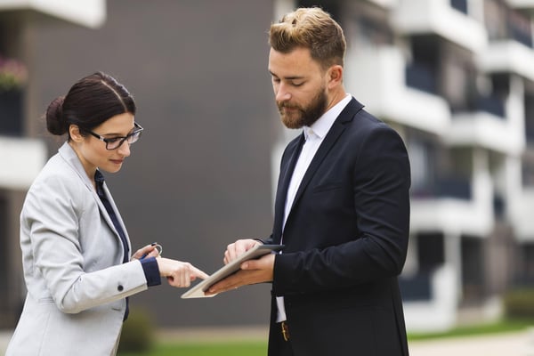 1 businessman and businesswoman outdoors the woman is signing a document on a tablet