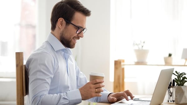 Happy person drinks coffee at their desk