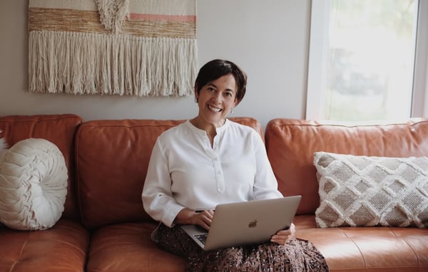 Happy woman on leather couch with computer