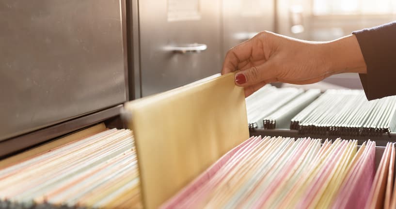 Hand zieht Akte aus einem Aktenschrank