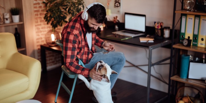Man working at desk with his dog jumping up to interrupt