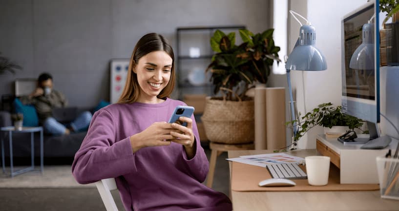 Woman working from home with a smartphone in her hand