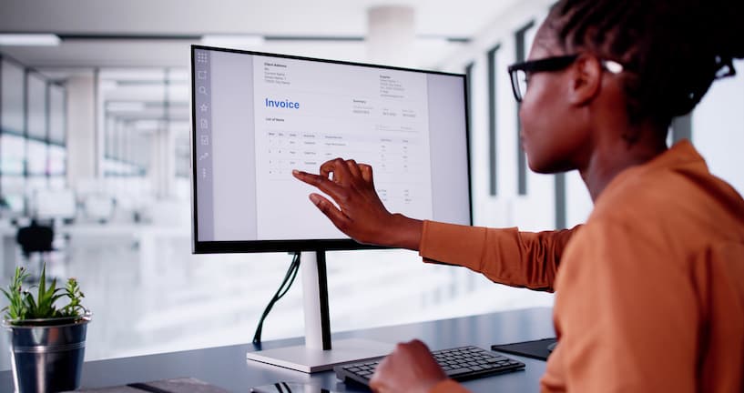 Woman at her desk looking towards the monitor at a digital invoice