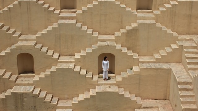 A women dressed in white standing in a maze of stairs